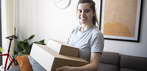 Portrait of smiling young woman holding delivery boxes at home