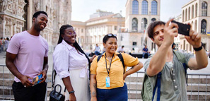 Tourists taking photos with tour guide in front of Duomo in city of Milan, Italy