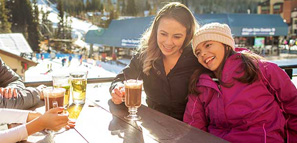 Mother and daughter laughing and having drinks at a ski resort